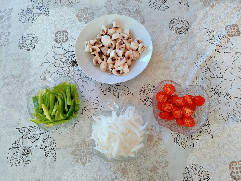 champignons, poivrons verts, oignon et tomates cerises coupés dans des récipients.
